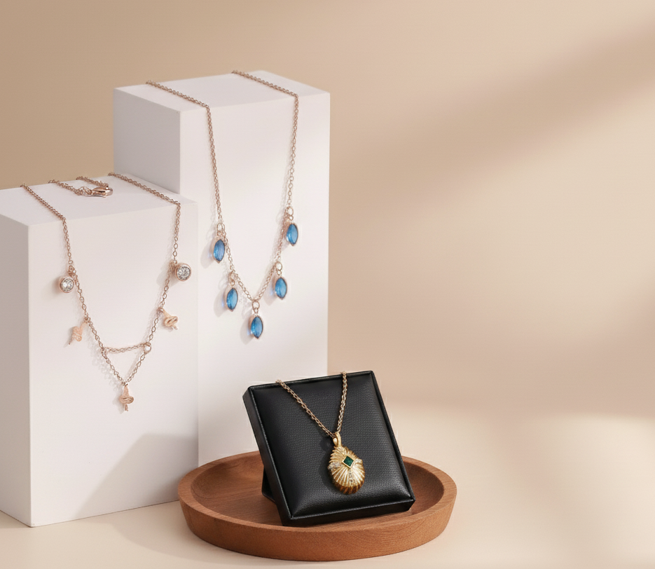 Two necklaces displayed on a beige background with a white box and wooden tray.